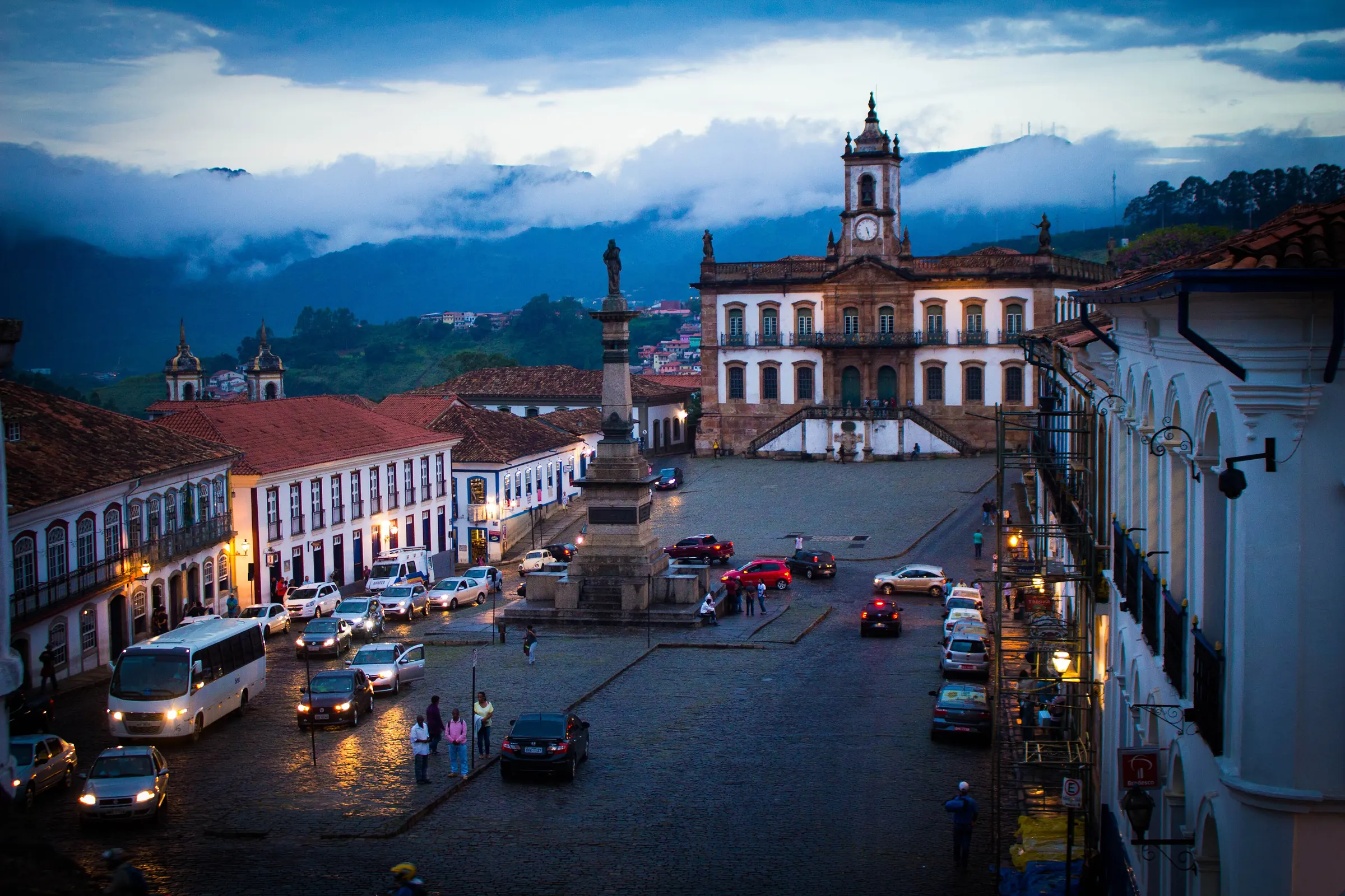 Praça Tiradentes ao entardecer, com o Museu da Inconfidência, o monumento a Tiradentes e as serras cobertas de nuvens